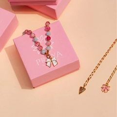 Jewelry set on pink Praya boxes with a gold chain and pink beads on a beige background