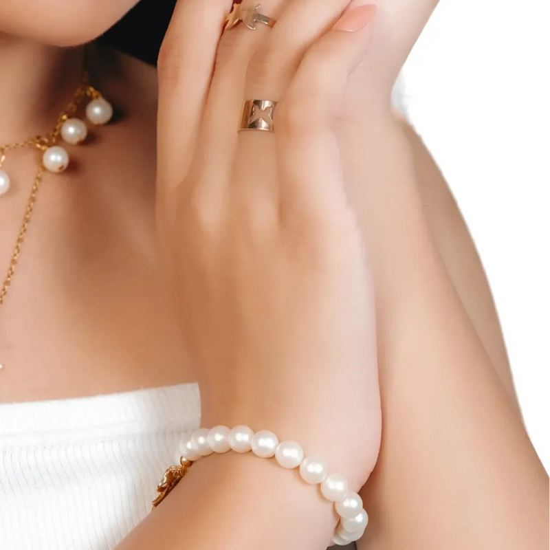 Woman wearing pearl necklace and bracelet with a white background