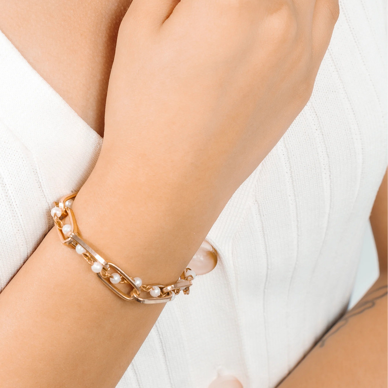 Gold necklace, ring, and bracelet on a person against a white background